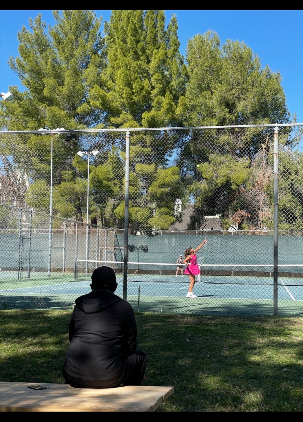 Kristina Liutova practising while Sean Bollettieri watches from a bench